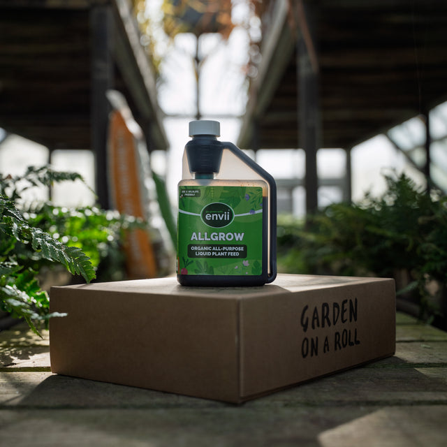 Envii Allgrow organic all-purpose liquid plant feed displayed on a Garden on a Roll box in a greenhouse.
