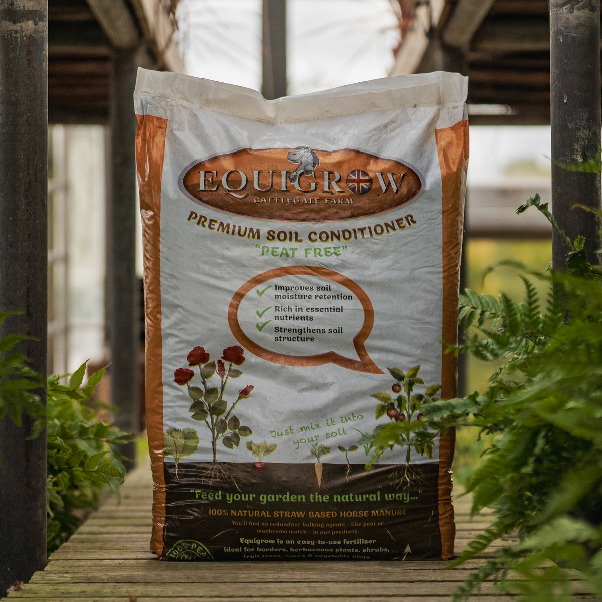 Bag of Equigrow peat-free premium soil conditioner made from natural straw-based horse manure, displayed among garden ferns.